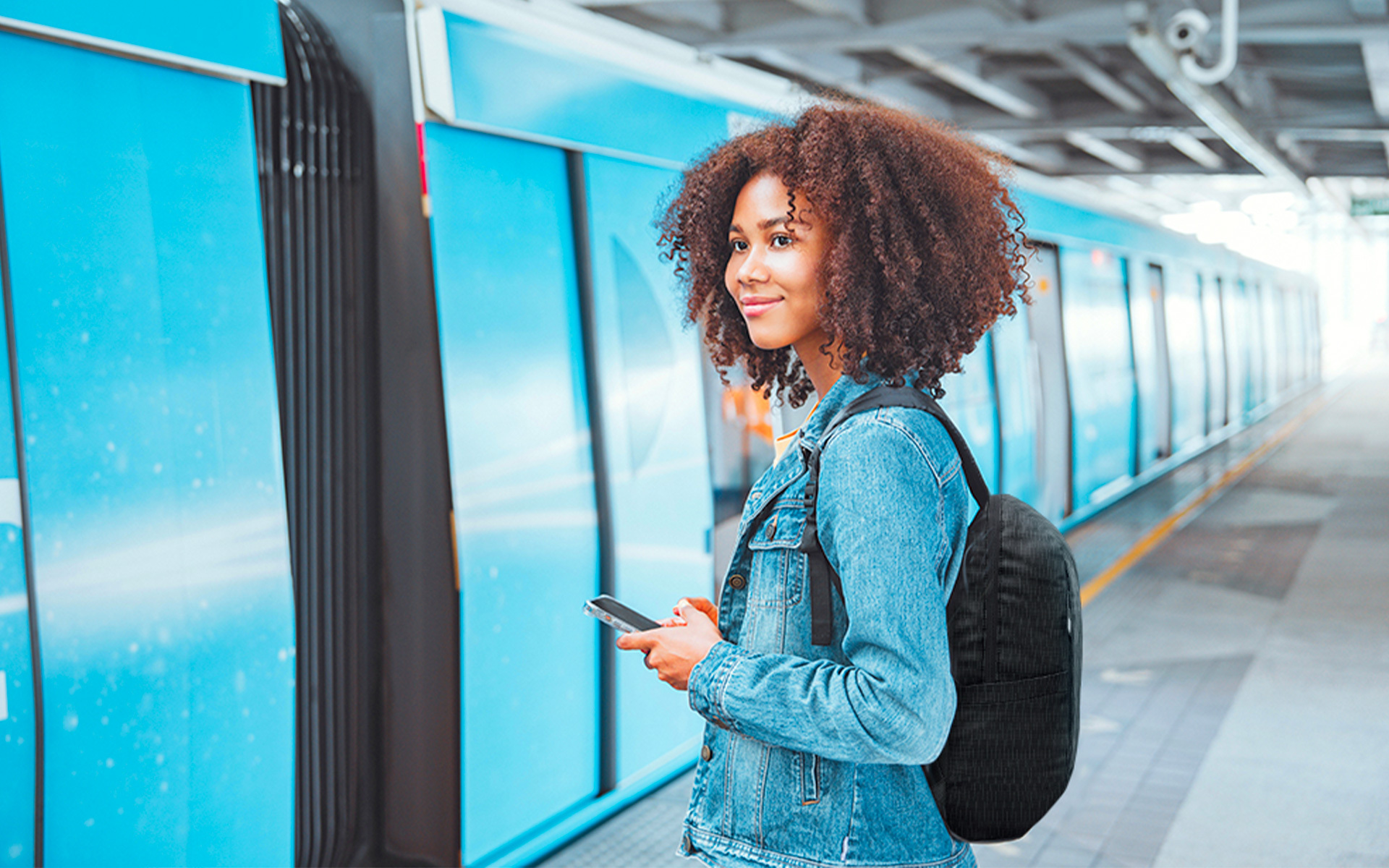 Young woman with Bagpack and smartphone, waiting to board train