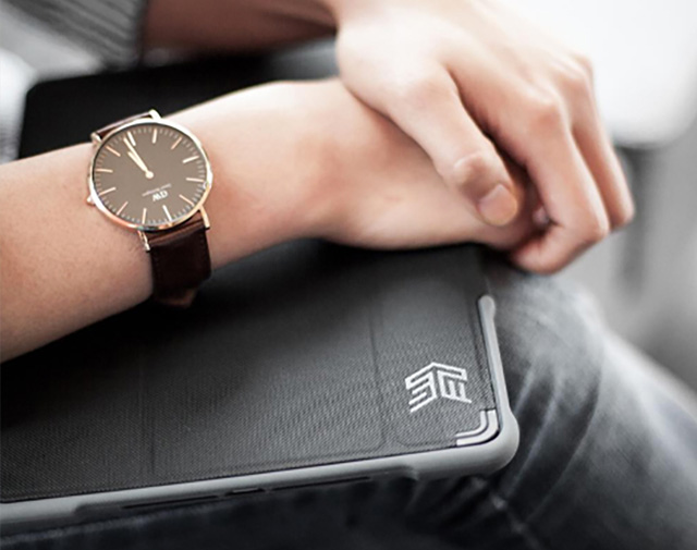 Crossed hands with wristwatch, resting on STM device case