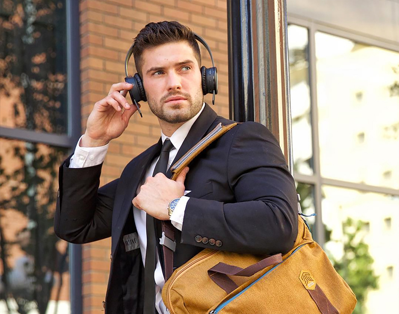 Man in suit, wearing headphones, with STM Goods laptop brief